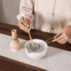 kit matcha céramique, une personne tamise du matcha à travers d'une passoire