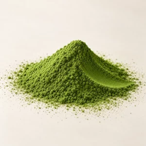 Poudre de matcha de cérémonie en monticule avec le creux d'une cuillère, vue de trois quarts sur fond crème